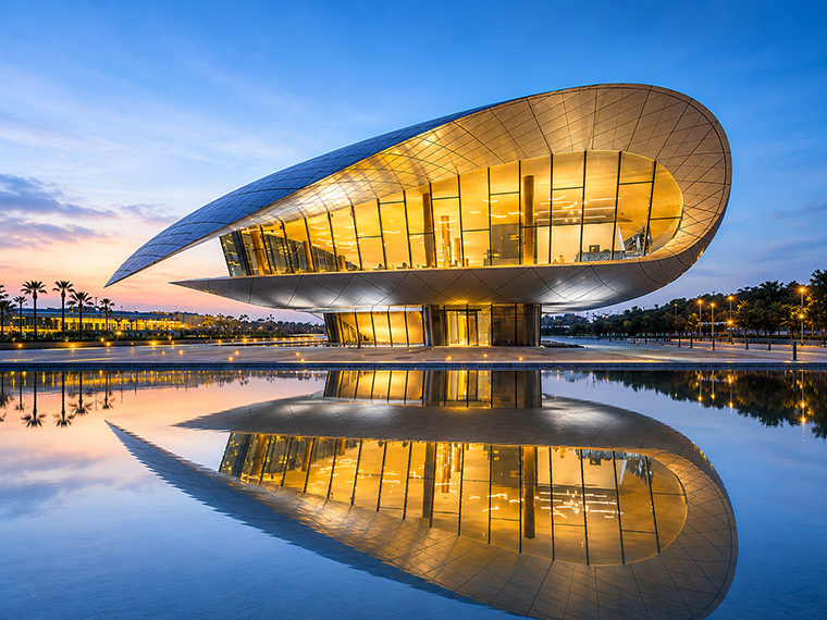 Главное здание музея Etihad Museum в Дубае с футуристической архитектурой и отражением в воде